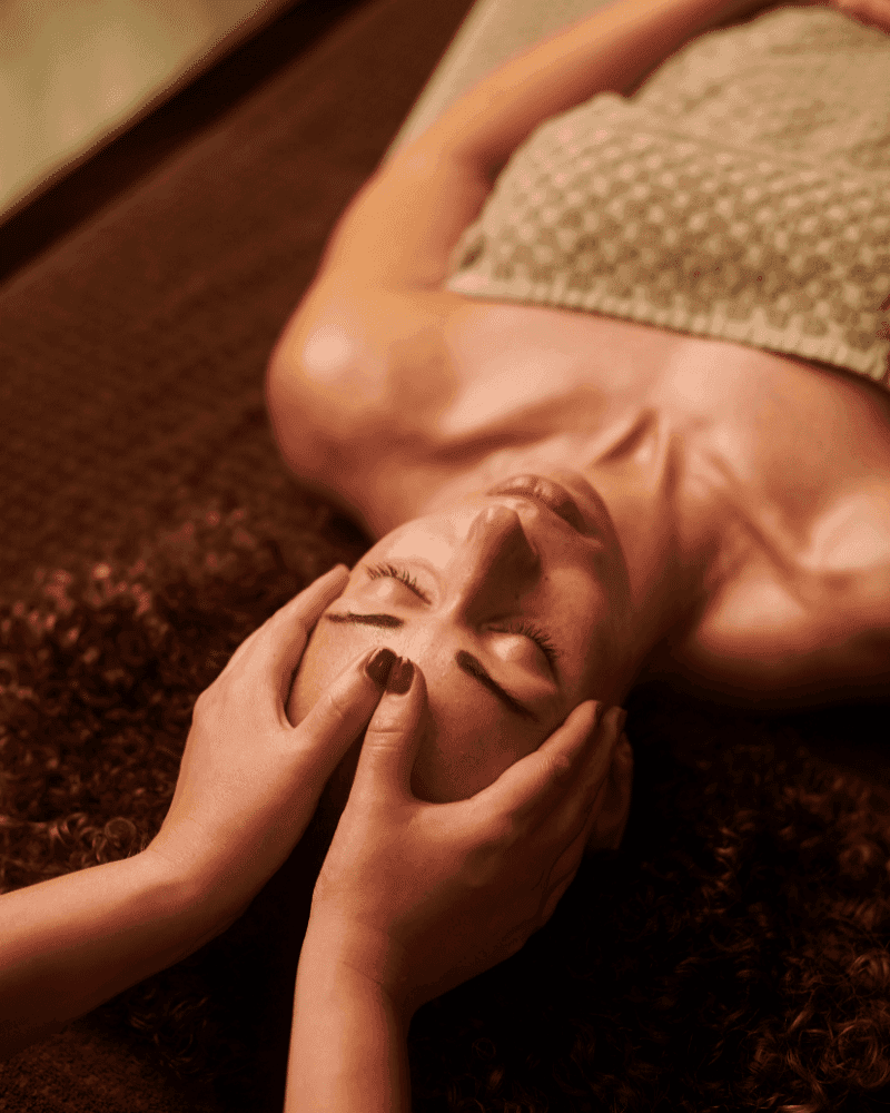 Person receiving a relaxing facial massage while lying on a spa bed.