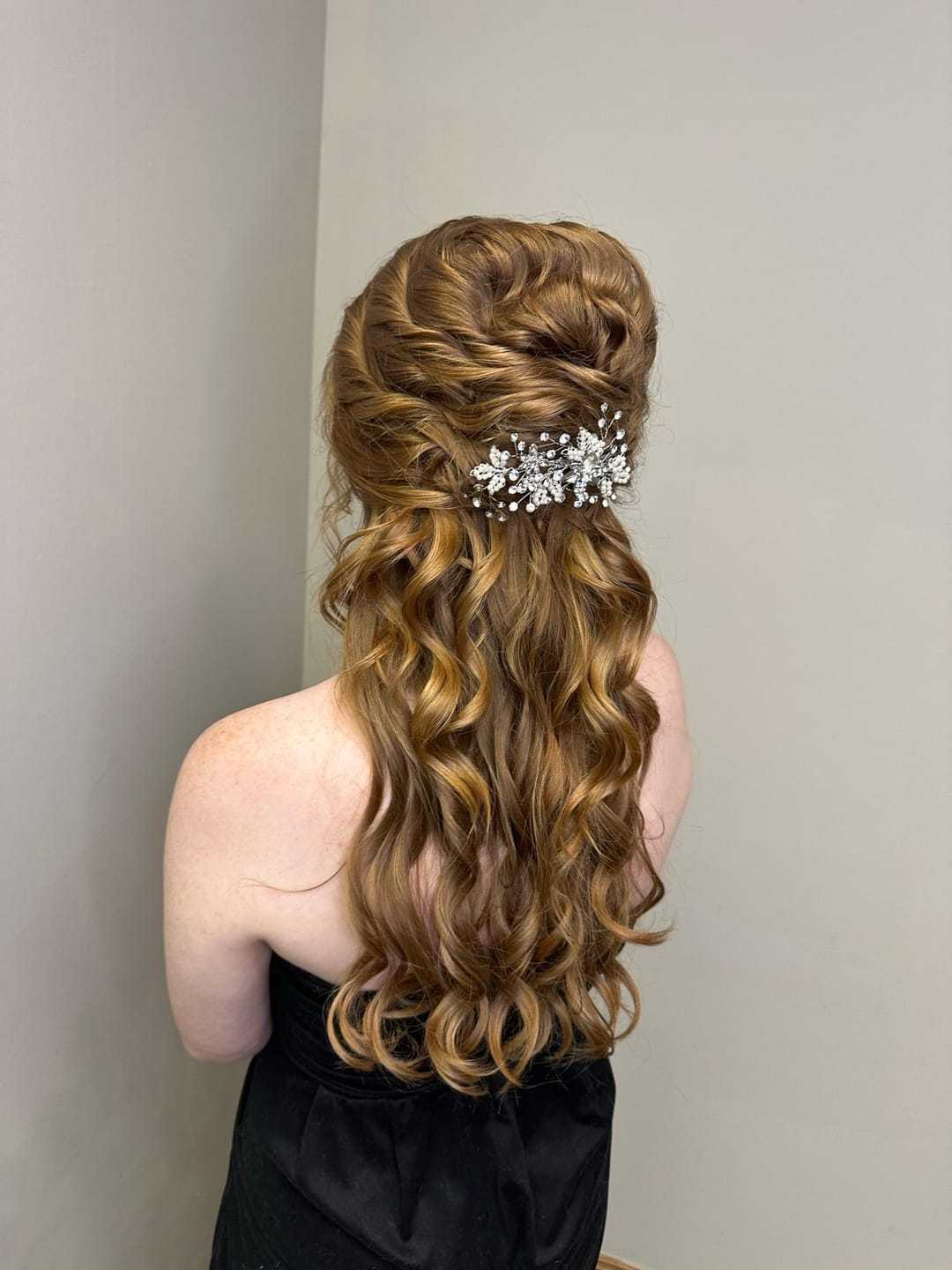 Woman in black dress with styled brown hair adorned with a decorative hair clip.