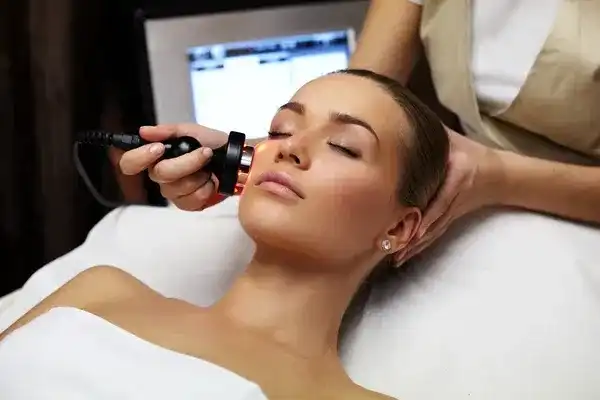 Woman receiving a facial treatment with a modern skincare device at a spa.