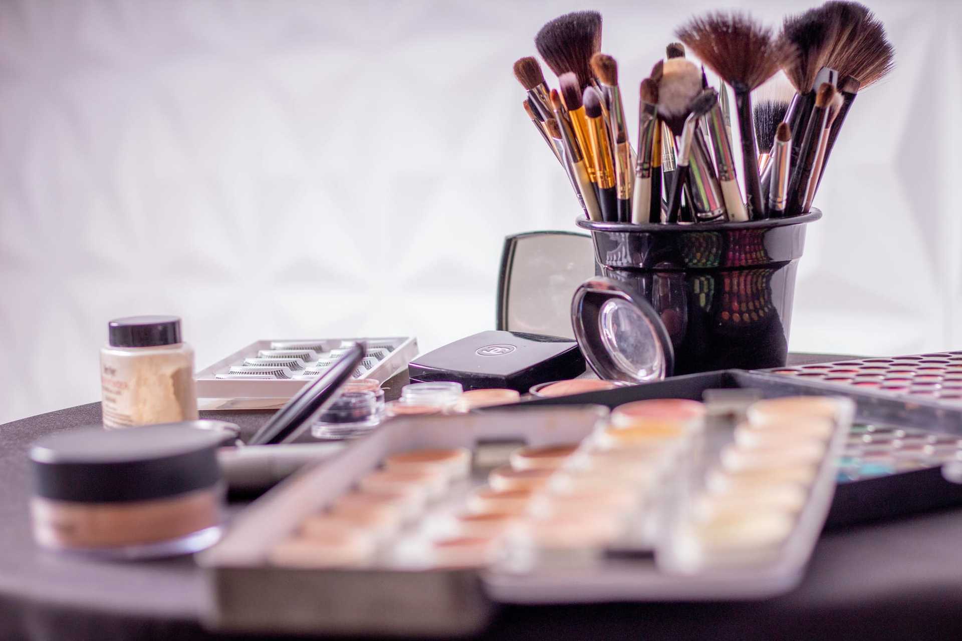 Assorted makeup brushes and cosmetics in black container on a table.