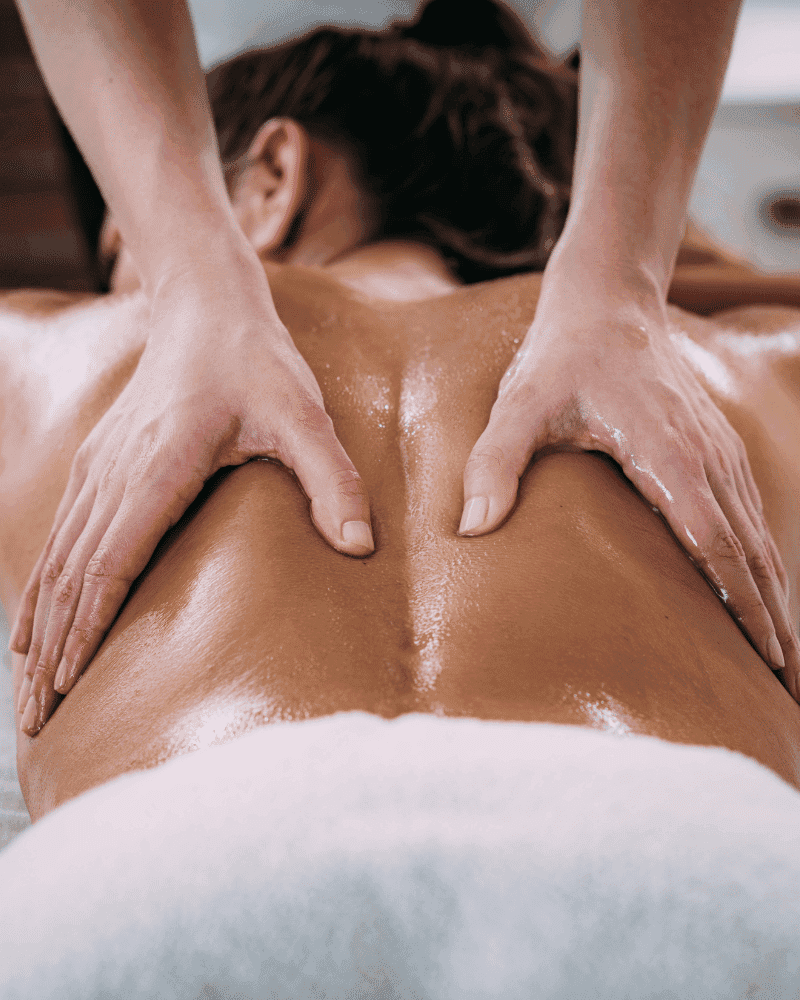 Person receiving a relaxing back massage, with hands applying oil and gentle pressure.